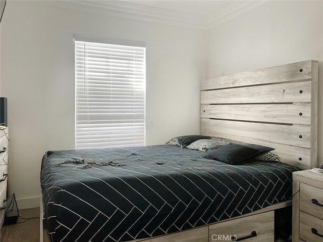 bedroom featuring baseboards, ornamental molding, and wood finished floors