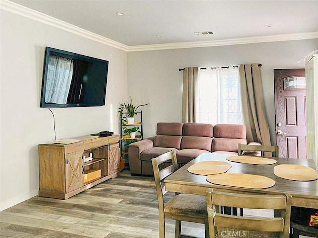 dining area with ornamental molding, light wood-type flooring, visible vents, and baseboards