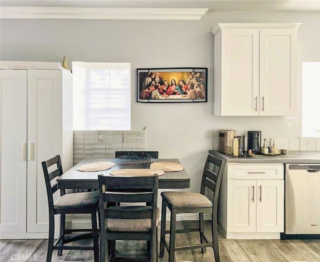 dining area featuring light wood-style floors and ornamental molding