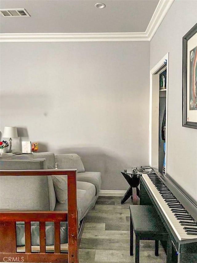 living area featuring baseboards, visible vents, crown molding, and wood finished floors