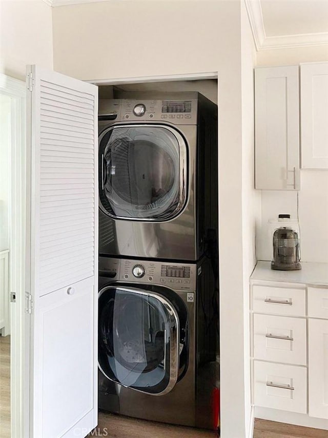 laundry room featuring laundry area, crown molding, light wood finished floors, and stacked washer / dryer