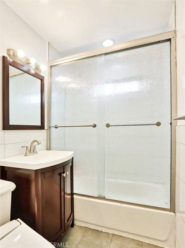 bathroom with backsplash, toilet, combined bath / shower with glass door, vanity, and tile patterned floors