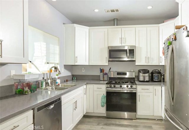 kitchen featuring white cabinets, visible vents, stainless steel appliances, and a sink