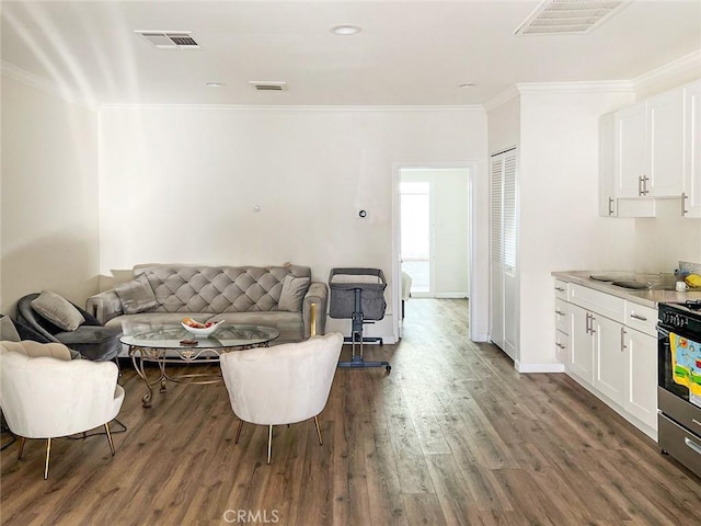 living room featuring wood finished floors, visible vents, and crown molding