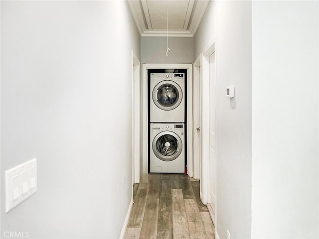 laundry area featuring attic access, laundry area, stacked washing maching and dryer, and wood finished floors