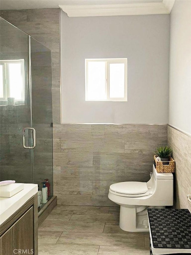 full bathroom featuring wainscoting, toilet, wood finish floors, a shower stall, and tile walls