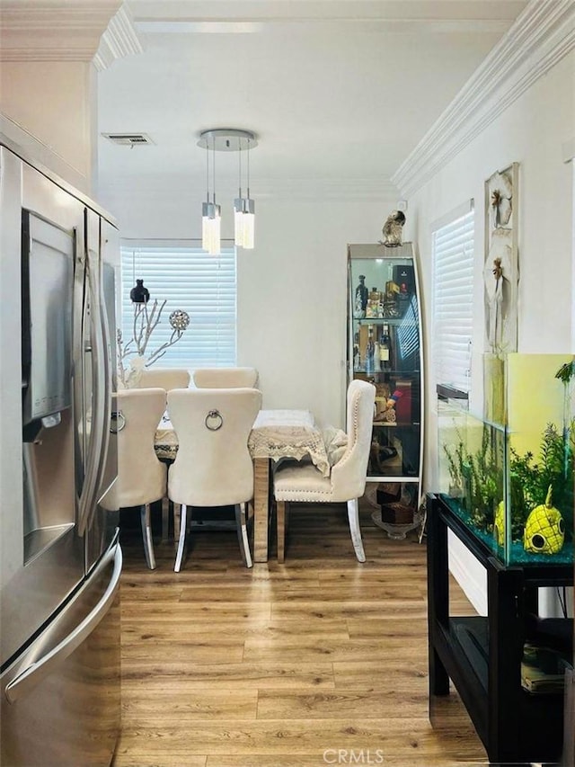 dining room featuring light wood-style floors, visible vents, and ornamental molding