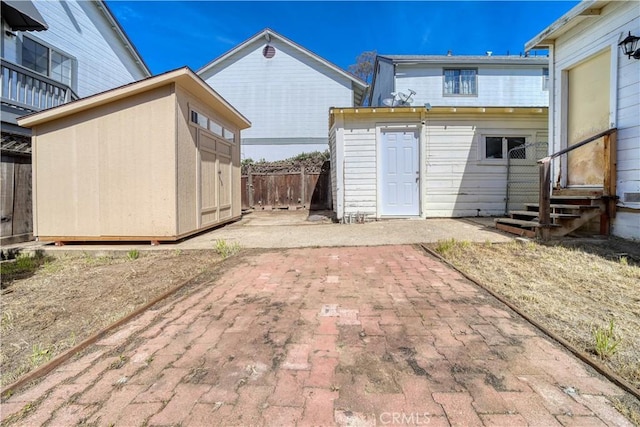 rear view of property with a patio, a storage unit, entry steps, fence, and an outdoor structure