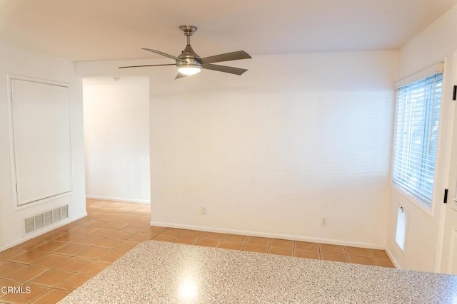 empty room with light tile patterned floors, ceiling fan, visible vents, and baseboards