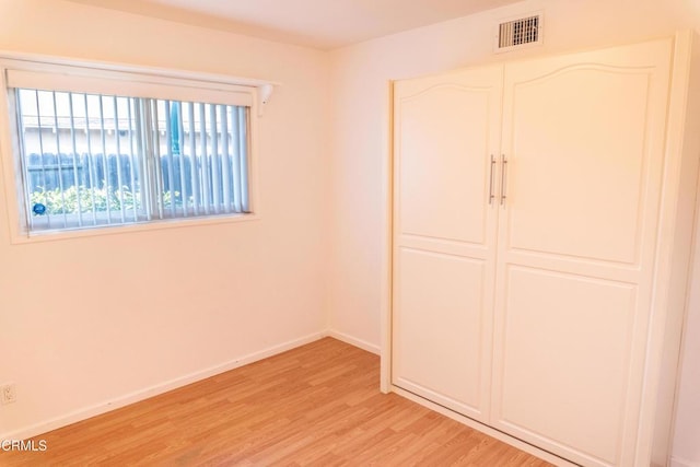 unfurnished bedroom featuring a closet, visible vents, light wood-style flooring, and baseboards