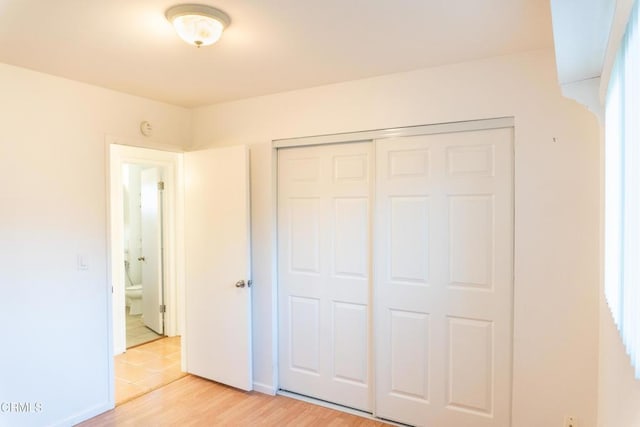 unfurnished bedroom with a closet, light wood-type flooring, and baseboards