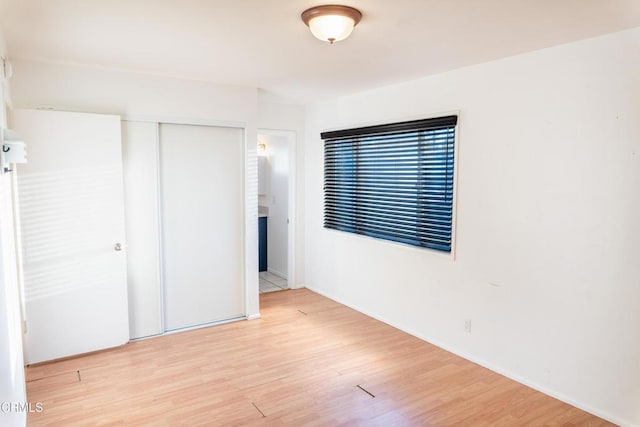 unfurnished bedroom featuring light wood-style floors and a closet