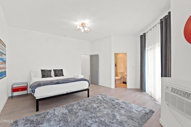 bedroom featuring ensuite bath, wood finished floors, and baseboards