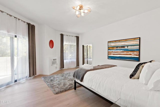 bedroom featuring light wood-type flooring, multiple windows, and a wall mounted AC