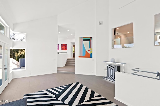 interior space with high vaulted ceiling, a wealth of natural light, and french doors