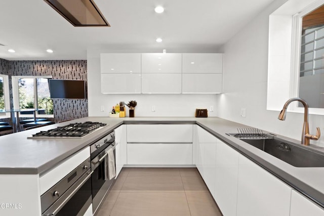 kitchen featuring tile patterned flooring, a sink, white cabinets, appliances with stainless steel finishes, and modern cabinets