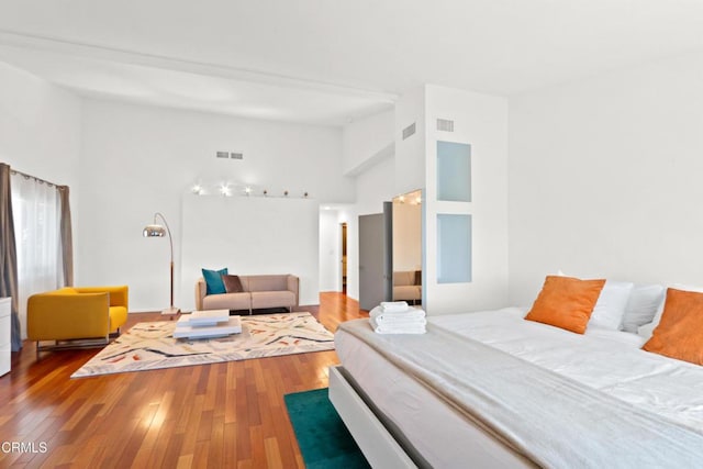 bedroom with high vaulted ceiling, hardwood / wood-style flooring, and visible vents