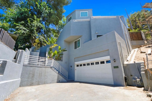 view of front of property featuring a garage, driveway, stairs, and stucco siding