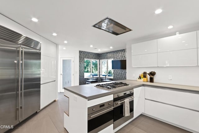 kitchen with a peninsula, white cabinetry, modern cabinets, and appliances with stainless steel finishes