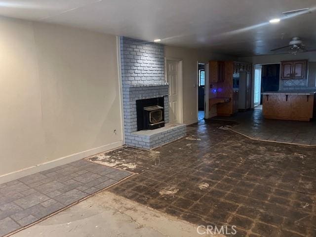 unfurnished living room featuring a ceiling fan and baseboards