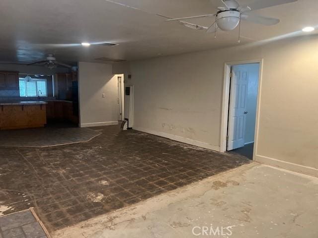 empty room featuring a sink, a ceiling fan, and baseboards