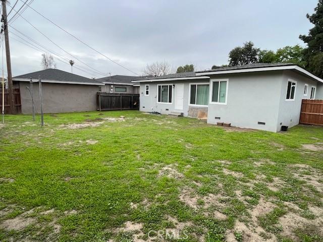 back of house featuring crawl space, stucco siding, a fenced backyard, and a yard