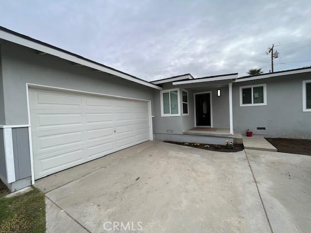 ranch-style house with concrete driveway, an attached garage, and stucco siding