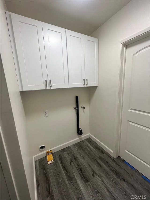 laundry room featuring dark wood-style flooring, cabinet space, and baseboards