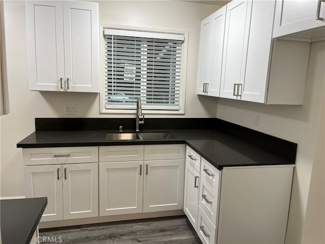 kitchen with dark countertops, white cabinetry, and a sink