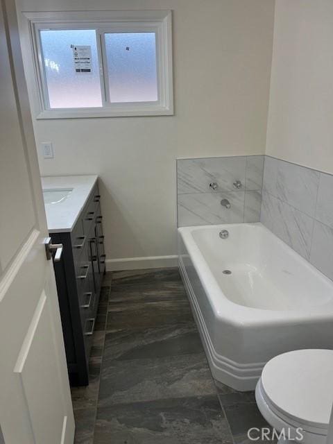 bathroom featuring baseboards, toilet, wood finished floors, a garden tub, and vanity