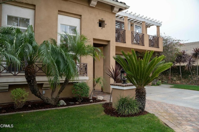 exterior space with stucco siding, a balcony, and a pergola