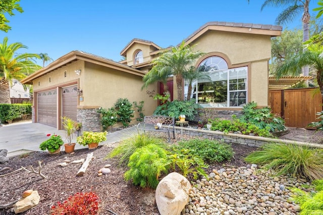 view of front of house featuring a garage, fence, driveway, stone siding, and stucco siding