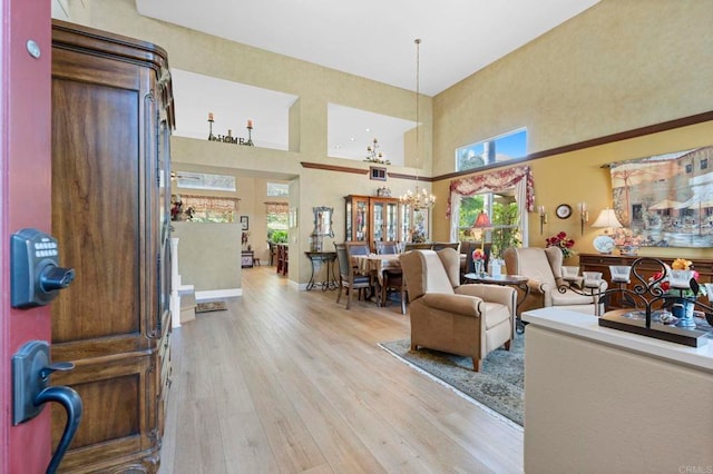 living room with a notable chandelier, a towering ceiling, and wood finished floors