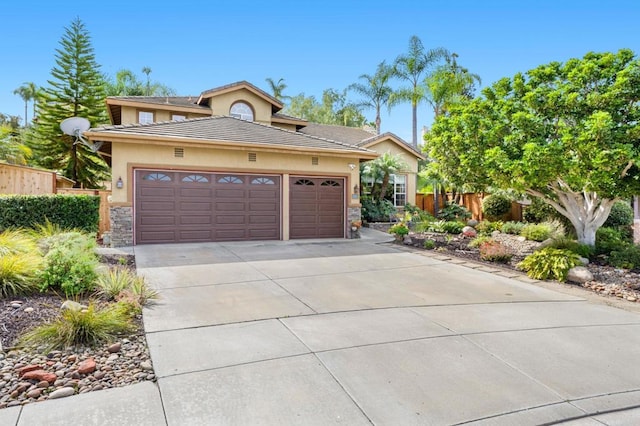 view of front of home featuring driveway, a garage, stone siding, fence, and stucco siding