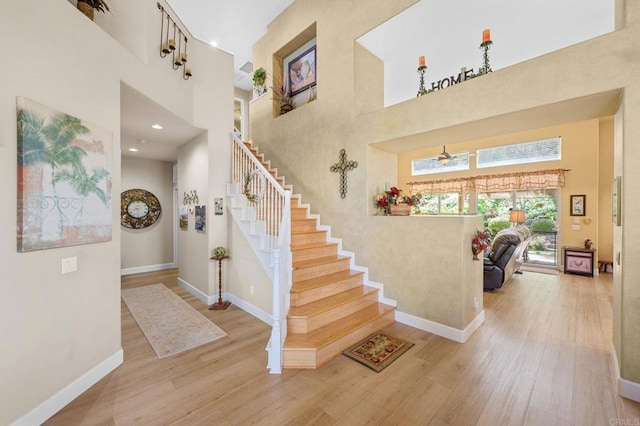 entryway with a high ceiling, stairway, wood finished floors, and baseboards