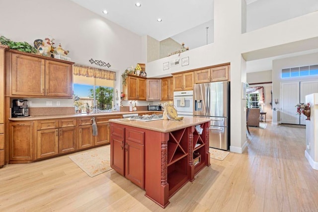 kitchen with light countertops, light wood-type flooring, stainless steel fridge, and brown cabinets