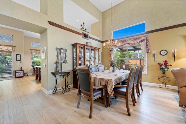 dining area featuring light wood finished floors, baseboards, a wealth of natural light, and an inviting chandelier