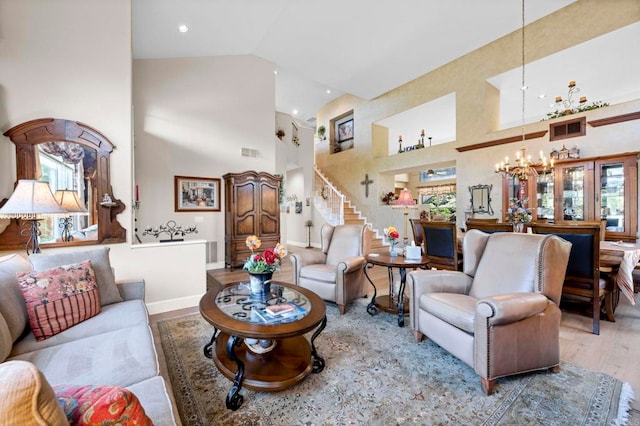 living room with high vaulted ceiling, wood finished floors, visible vents, and an inviting chandelier