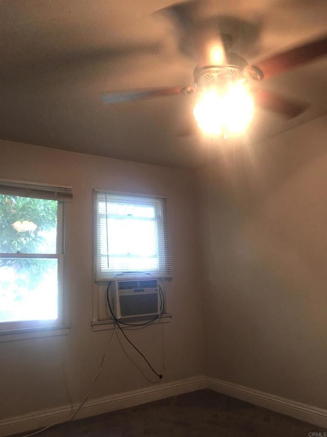 empty room featuring cooling unit, a ceiling fan, and baseboards