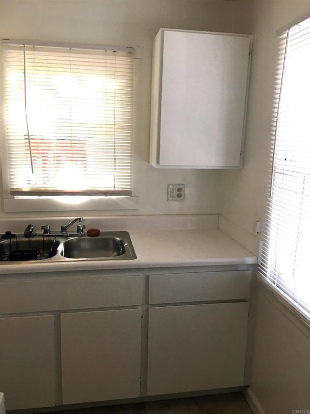 kitchen featuring white cabinetry, light countertops, and a sink