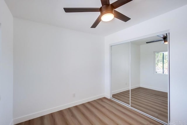 unfurnished bedroom with a closet, wood finished floors, a ceiling fan, and baseboards