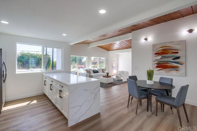 kitchen featuring a peninsula, light wood finished floors, white cabinetry, and light stone counters