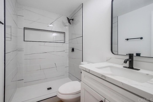 bathroom featuring toilet, a marble finish shower, and vanity