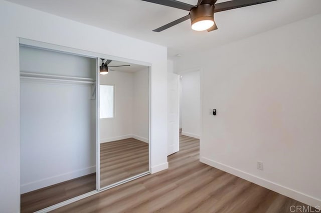 unfurnished bedroom featuring a closet, wood finished floors, a ceiling fan, and baseboards