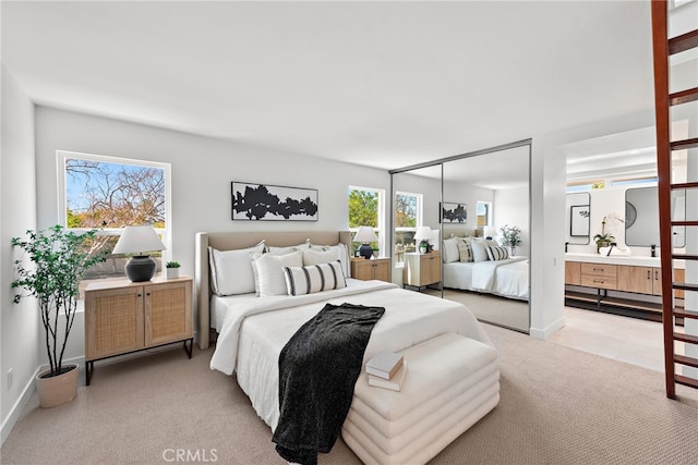 bedroom featuring light colored carpet, connected bathroom, and baseboards