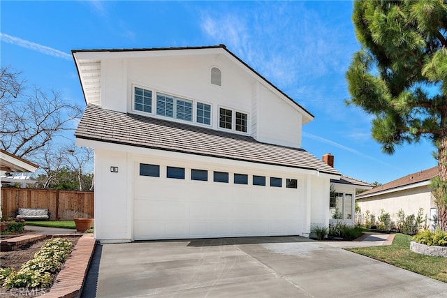 view of front of house with fence, concrete driveway, and stucco siding