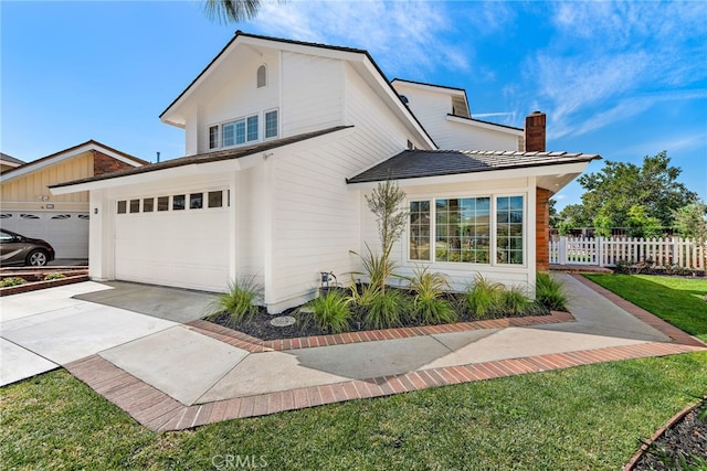 view of front of property with concrete driveway, fence, a chimney, and an attached garage