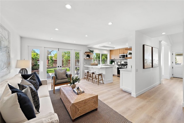 living room featuring recessed lighting, french doors, plenty of natural light, and light wood-style flooring