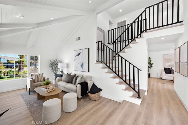 living area with high vaulted ceiling, wood finished floors, visible vents, baseboards, and beam ceiling