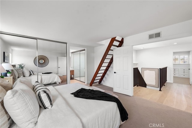 bedroom featuring wood finished floors, carpet, two closets, and visible vents